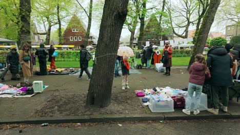 Stalls-displayed-during-King's-Day-in-Amsterdam-and-people-walking-around-travel-to-right