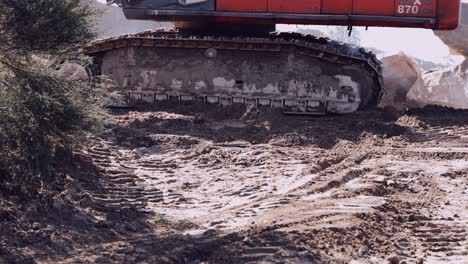 Crawler-excavator-tracks-caked-in-mud-on-a-construction-site