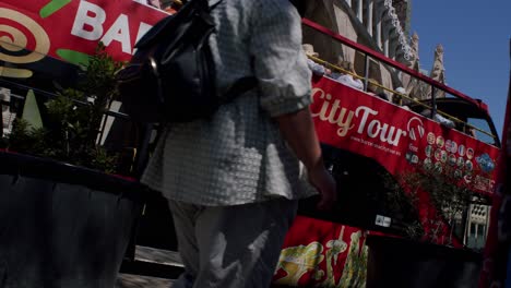 Red-double-decker-Barcelona-City-Tour-bus-in-sunlit-street,-dynamic-angle