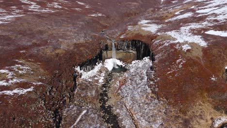 Volcanic-hole,-Icelandic-earth-landscape-Svartifoss-waterfall,-drone-reveals-sky