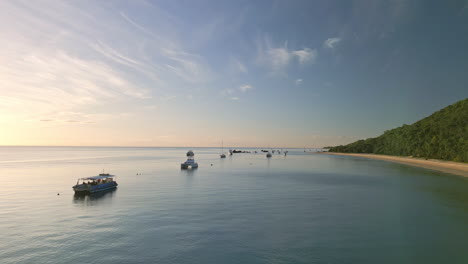 Sunset-Skyline,-Boats-float-still,-drone-fly-low-Natural-Beach-Moreton-Island,-Australian-marine-travel-destination