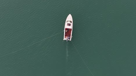 Solitary-boat-on-the-emerald-waters-of-Walensee,-Swiss-serenit---aerial-top-down-view
