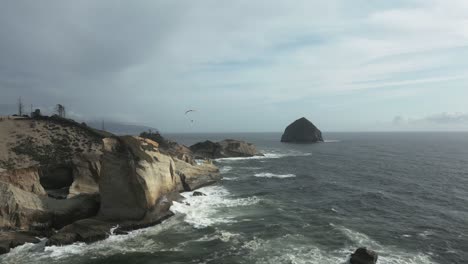 Cape-Kiwanda-shore-with-stormy-waves-and-paraglider-above-coast,-Oregon-coast,-USA
