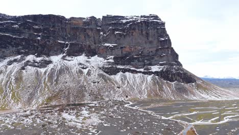 Earthy-Volcanic-Cliff-Landscape-in-Iceland,-Snowy-Mountain-skyline-background,-slow-motion-revealing-panorama-of-nordic-natural-reserve