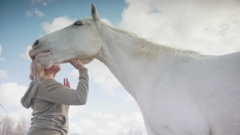 Una-Mujer-Acaricia-Debajo-De-La-Mandíbula-De-Un-Caballo-Blanco-Durante-La-Terapia-Asistida-Por-Caballos,-Ver-Arriba