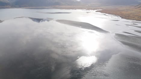 Luftdrohne-Fliegt-über-Der-Sonne,-Die-Sich-Im-Schwarzen-Gletscherfluss-Der-Isländischen-Küste-Und-Dem-Vulkanischen-Boden-Spiegelt