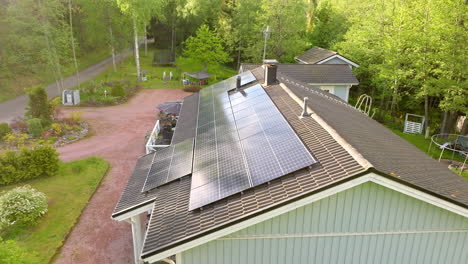 Reflecting-solar-modules-on-a-modern-house-roof,-sunny,-summer-day---Drone-shot