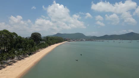 Wide-empty-Bang-Saray-Beach-in-Thailand-with-small,-colorful-fishing-boats-anchored-in-turquoise-water