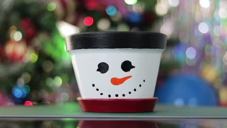 DIY-plant-pot-colored-as-snowman-with-festive-Christmas-lights-background,-zoom-in