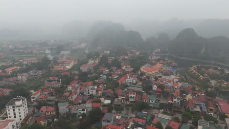 Vietnam's-Ninh-Binh-Province:-Misty-aerial-drone-photo-of-buildings-and-a-house-near-hills