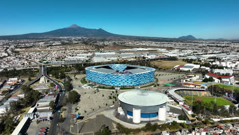 Aerial-view-tilting-toward-the-Football-Soccer-Stadium,-in-sunny-Puebla,-Mexico