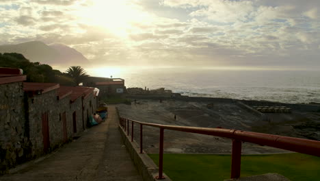 Historic-buildings-of-Hermanus-Old-Harbour,-vibrant-sunrise-over-Walker-Bay