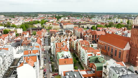 Overhead-view-of-Elbląg's-city-center-with-a-mix-of-modern-and-historic-buildings,-a-prominent-church,-and-a-bustling-street