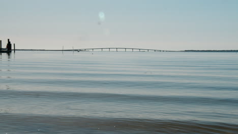 Olas-Vidriosas-Ruedan-Bajo-Un-Puente-Distante-En-El-Horizonte