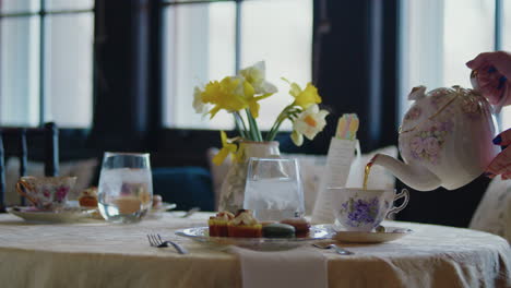 Classy-tea-table-with-yellow-daffodils-and-pastries-softly-lit-by-the-windows