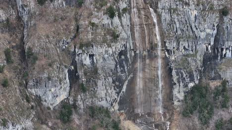 Aerial-view-of-Switzerland's-highest-waterfalls,-the-Seerenbach-Falls,-cascading-down-the-rocky-cliffs