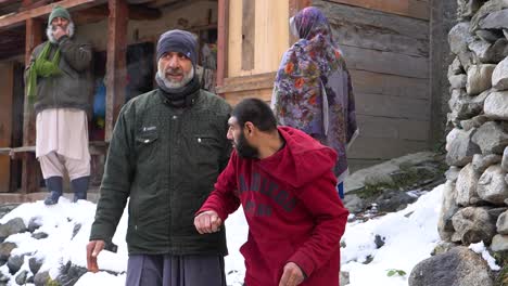 Man-supporting-a-microcephalic-boy-outdoors-in-winter,-snow-in-the-background