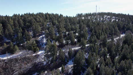 Vista-Aérea-Volando-Sobre-Una-Ladera-De-Una-Montaña-De-Nuevo-México-Cubierta-De-Nieve-Con-Una-Torre-Celular