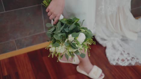 Bride-holding-a-lush-wedding-bouquet,-details-of-white-dress-and-sandals