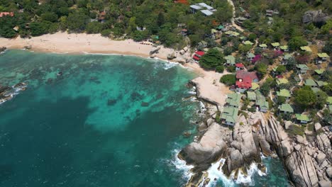 Atemberaubende-Filmische-Drohnenaufnahme-über-Einem-Wunderschönen-Tropischen-Strand-Mit-Ferienhäusern