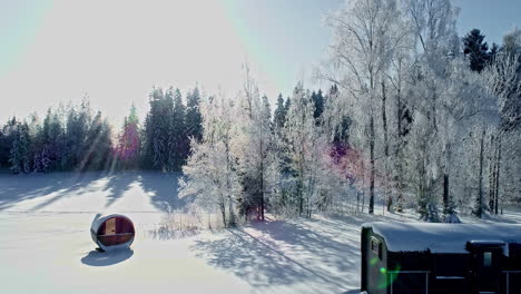 Cabin-house-on-a-side-of-the-frozen-lake-with-beautiful-winter-landscape,-aerial-view