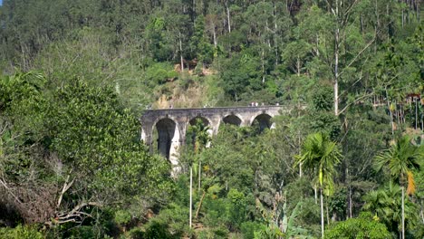 Slow-motion-SLR-landscape-view-of-Nine-Arch-Bridge-train-railway-crossing-in-rainforest-jungle-colonial-tourist-landmark-Ella-Kandy-Sri-Lanka-Asia-transport