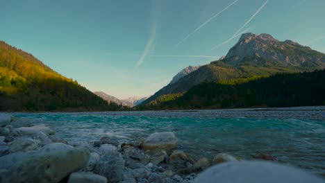 Clear-mountain-river-water-rushing-by-scenic-colorful-autumn-trees-in-the-evening-sun,-Austrian-alps