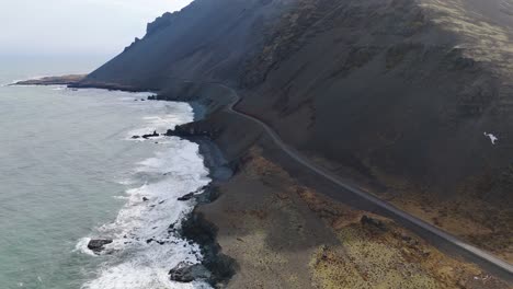 Volcanic-Black-Cliff-Atlantic-Ocean-Aerial-Panoramic-Waves-Crushing-Sand-Shore