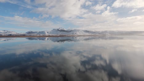 Volcanic-Iceland-travel-environment,-drone-fly-snowy-peaks-reflected-sunny-day