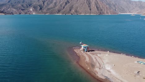 Aerial:-Rescue-building-on-barren-gravel-point,-Potrerillos-reservoir