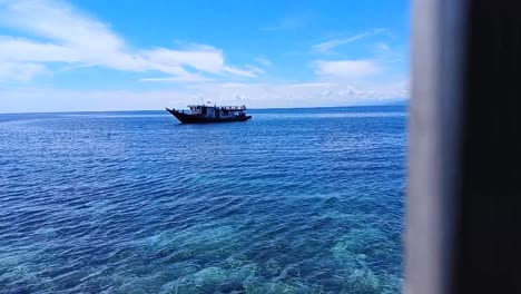 Pan-shot-of-Boats-floating-on-the-ocean-on-Karampuang-Island,-Mamuju,-West-Sulawesi,-Indonesia