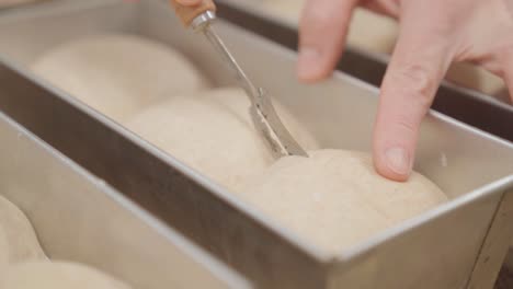 Scoring-fresh-bread-buns-with-a-knife,-homemade-bread