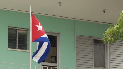 Cuban-flag-waving-in-wind-in-front-of-building-in-Havana,-Cuba