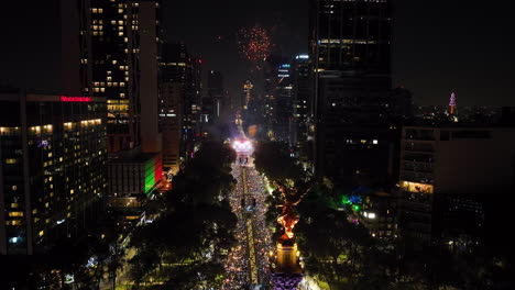 Night-of-fireworks-in-Mexico-city,-Aerial-view-of-crowded-streets-and-the-El-Angel-statue