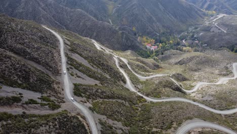 Vehicles-climb-dirt-road-to-mountain-pass-in-Villavicencio,-Argentina