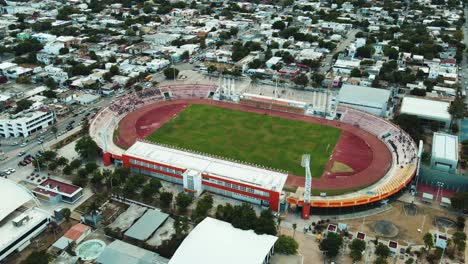 Hyperlapse-aerial-over-a-soccer-stadium-amidst-a-city-with-cars-and-people-in-motion