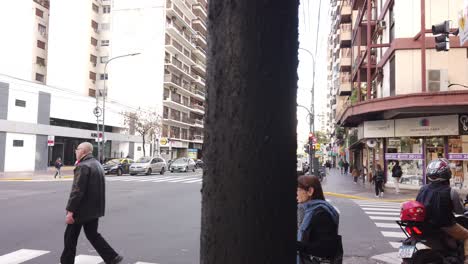 People-walk-at-Rivadavia-avenue-buenos-aires-city-bustling-asphalted-town-cars-drive-by-high-buildings-area,-argentina