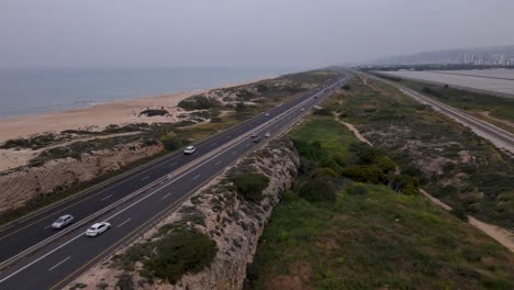 Coastal-road-with-traffic-near-beach-and-cliffs