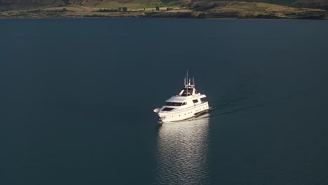 Beautiful-white-yacht-drives-smoothly-across-lake-reflection-in-water