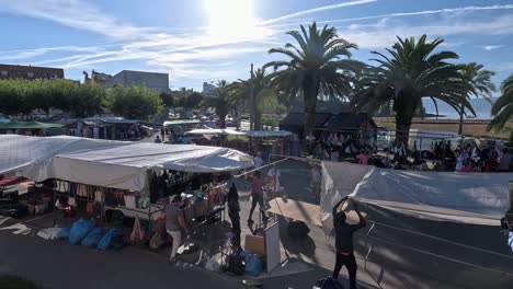 Street-lined-with-street-shops-set-up-to-sell-clothes,-food-and-fashion-accessories-to-tourists-near-the-beach,-overhead-shot-traveling-to-the-right