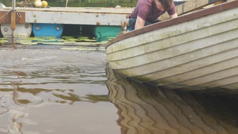Young-man-bails-water-from-fiberglass-fishing-boat