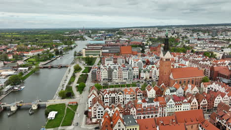 Aerial-forward-shot-of-Church-in-Polish-Town-and-Elblag-River-during-cloudy-day,-Poland