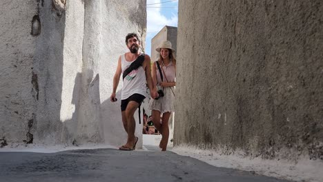 Liebespaar-Hält-Händchen-Und-Geht-In-Einer-Kleinen-Gasse-In-Santorini,-Griechenland