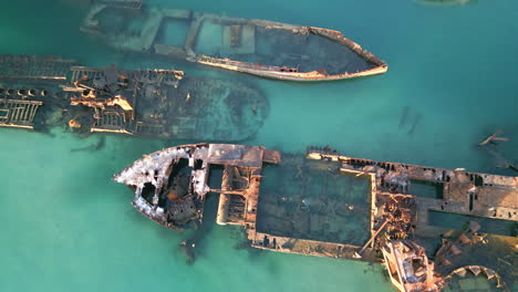 Drone-Top-Down-Closeup-rusted-ships,-shipwreck,-blue-water-ocean-aerial-sea-view,-marine-history-with-old-oxidized-vehicles