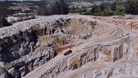 Camión-Cargado-Ascendiendo-Por-Un-Sinuoso-Camino-De-Cantera,-Destacando-La-Inmensidad-Del-Sitio-De-Excavación