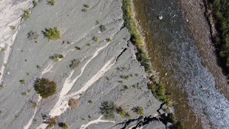 Bird's-eye-view-of-shallow-rocky-river-and-gravel-shoreline,-aerial
