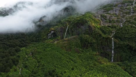 Snaking-waterfalls-wrap-along-cliff-edge-of-tropical-jungle-in-Milford-Sound