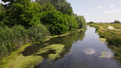 Low-drone-flight-over-stagnant-stream-near-rural-village-of-Batya,-Hungary