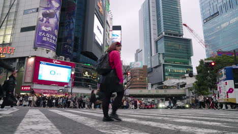 Chica-Cruzando-Una-Concurrida-Calle-De-La-Ciudad-En-Tokio,-Japón---Toma-De-Seguimiento