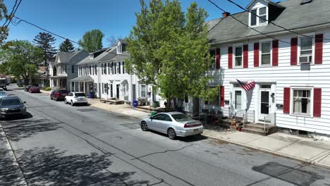 Pickup-Truck-Fährt-Auf-Der-Straße-In-Einer-Kleinen-Amerikanischen-Stadt-Mit-Der-Flagge-Der-USA-An-Der-Hausfassade